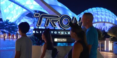 family walking in front of the sign for Tron Lightcycle Run in Disney World's Magic Kingdom park