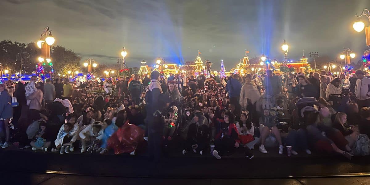 Guests gather after dark at Disney surrounded by glowing holiday lights and themed decorations sparkling throughout the park.