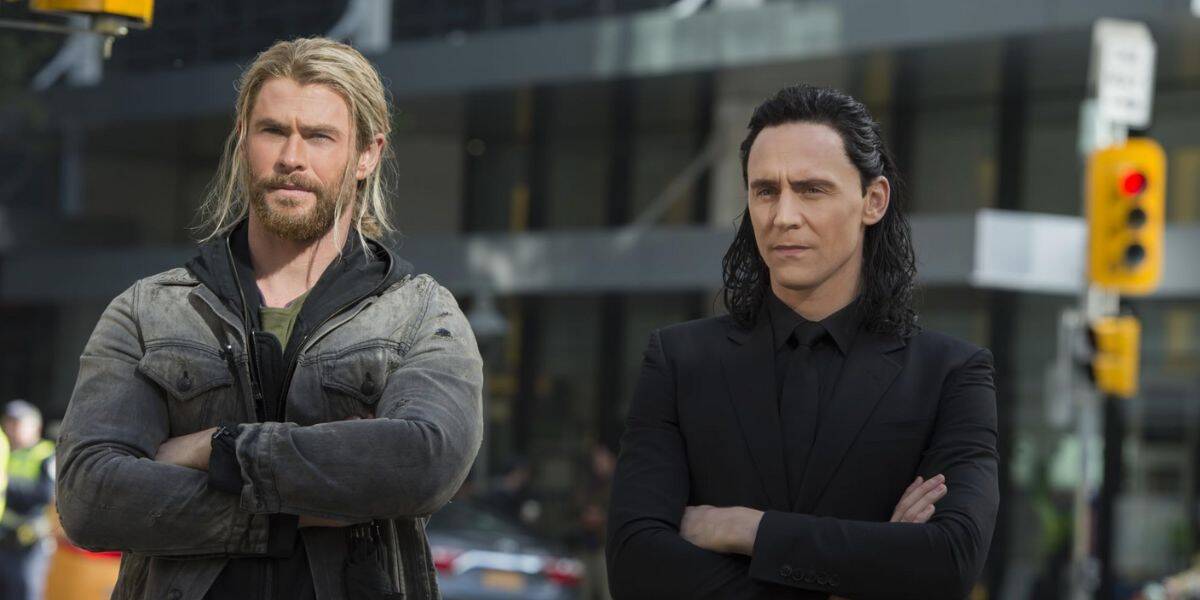 Two men channeling Thor and Loki pose heroically, arms crossed, on a bustling city street like a Marvel adventure at Avengers Campus.
