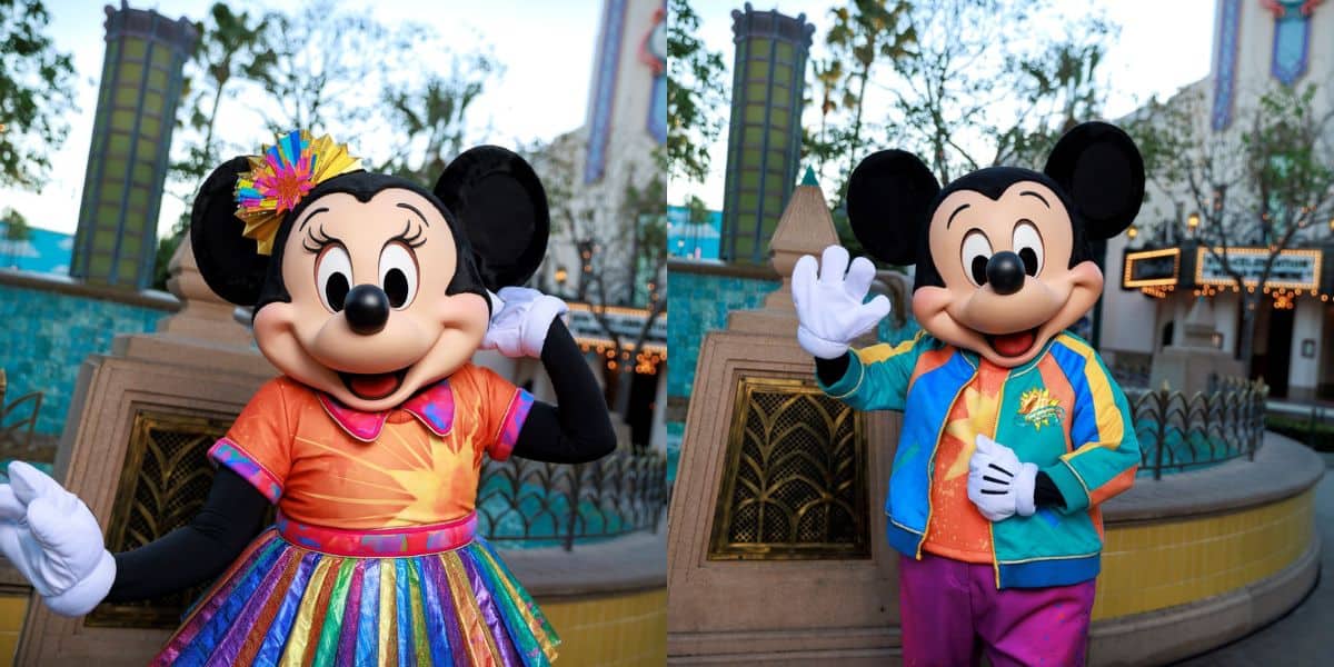 Mickey and Minnie Mouse in vibrant costumes greet fans with waves and smiles, celebrating a milestone at Disney Parks.