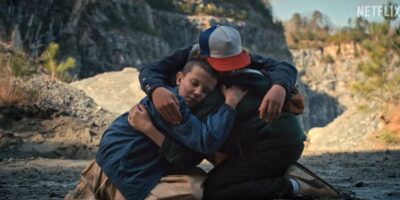 Eleven (Millie Bobby Brown) and her friends hugging in 'Stranger Things' Season 1
