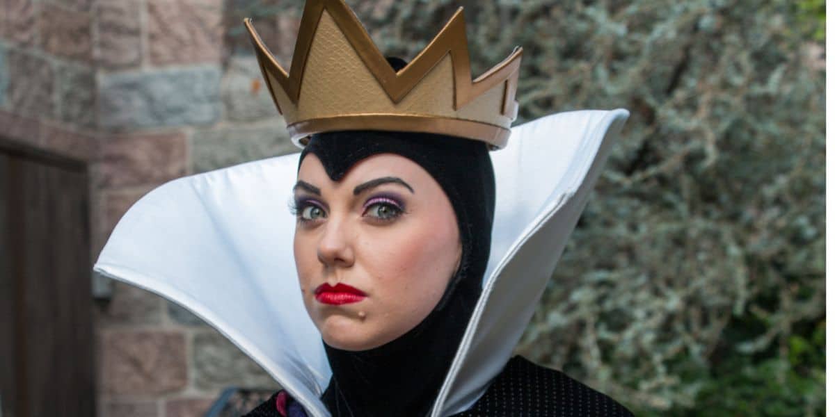 The Evil Queen from Snow White, in her signature gold crown and high white collar, greets guests at the park.