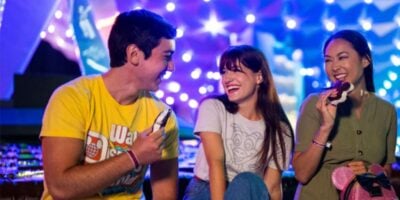 Three Disney World guests enjoy ice cream in front of EPCOT's Spaceship Earth at night