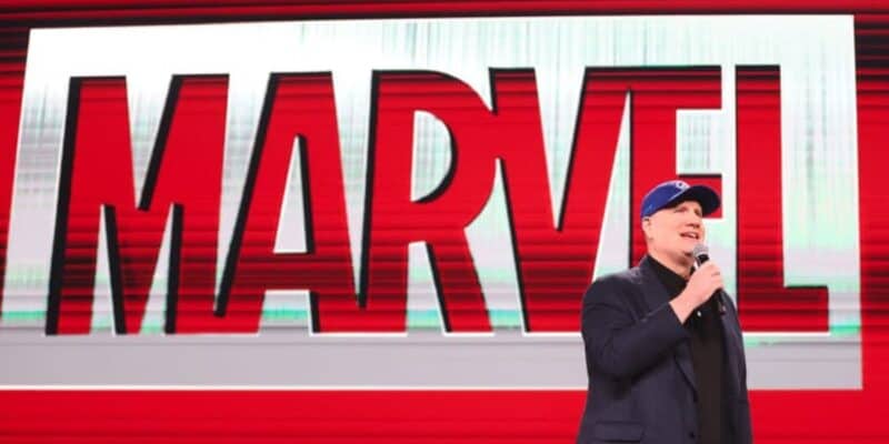 Kevin Feige takes the stage in his signature blue cap, addressing fans with Marvel’s iconic red logo glowing behind him.