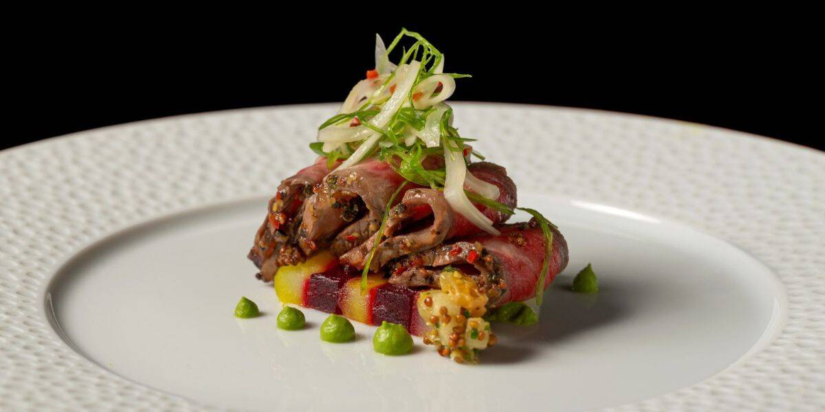 Whimsically plated entrée with rolled meat and veggies, dotted with green sauce—like culinary art at Disney’s finest eatery.