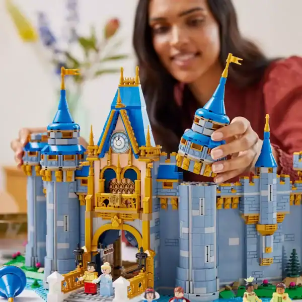 A guest builds the magical LEGO Disney Castle, adding a blue and gold turret—bringing iconic park magic home before it retires.
