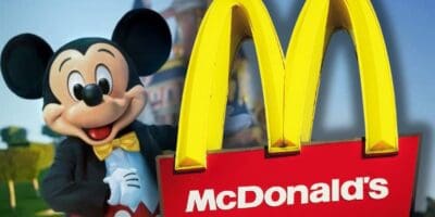 Mickey Mouse poses beside a giant McDonald's golden arches sign, blending Disney magic with familiar fast food fun.