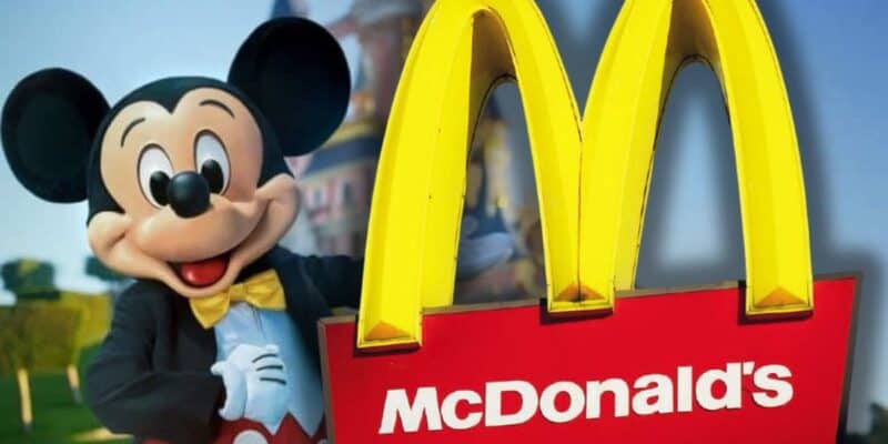 Mickey Mouse poses beside a giant McDonald's golden arches sign, blending Disney magic with familiar fast food fun.