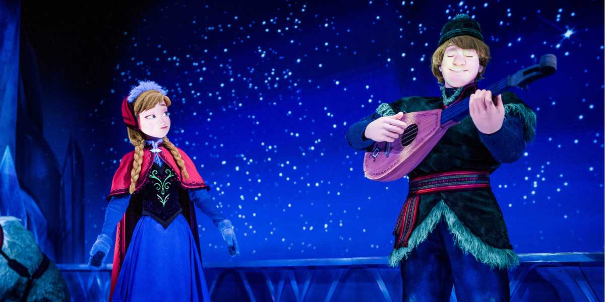 Anna admires Kristoff strumming a lute beneath EPCOT’s Frozen Ever After night sky