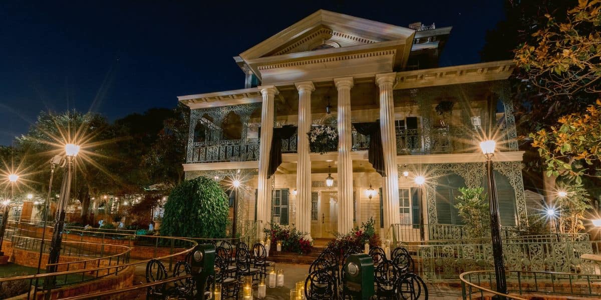 The Haunted Mansion glows with street lamps at night, its columns and ironwork creating Disney’s perfect spooky wedding backdrop.