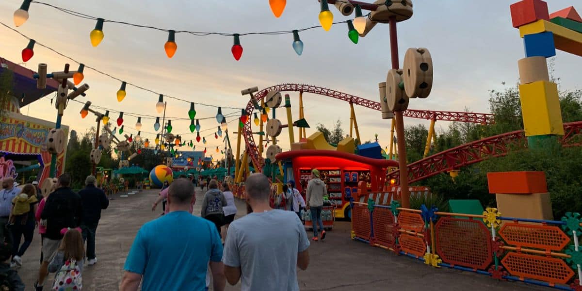 Guests walking through Toy Story Land at sunset.