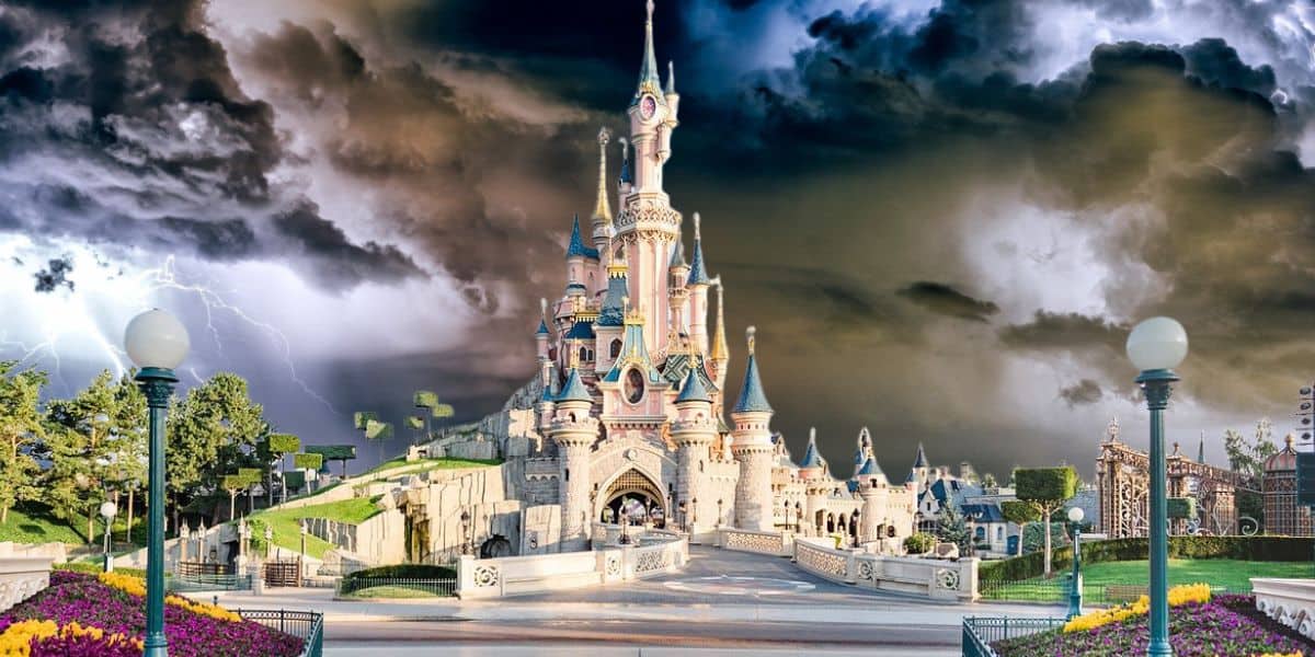An enchanting castle towers at the center of the park, framed by stormy skies and lightning for a thrilling fairytale adventure. Disney Parks weather disruption.