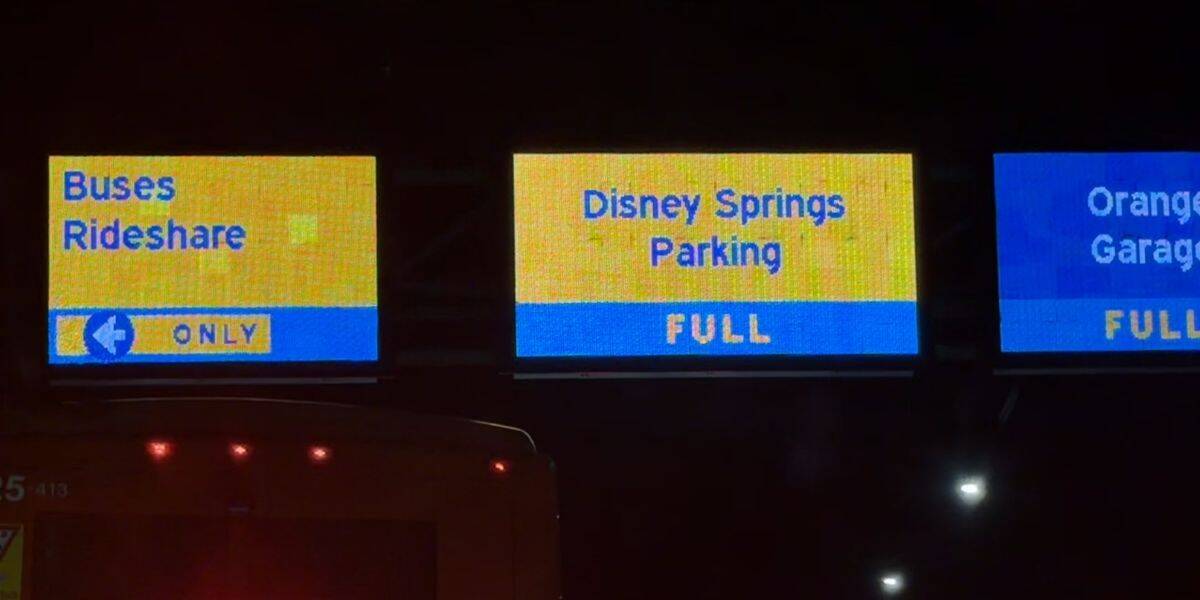 Nighttime electronic displays at Disney Springs show "Buses Rideshare," and alert guests both parking garages are FULL.