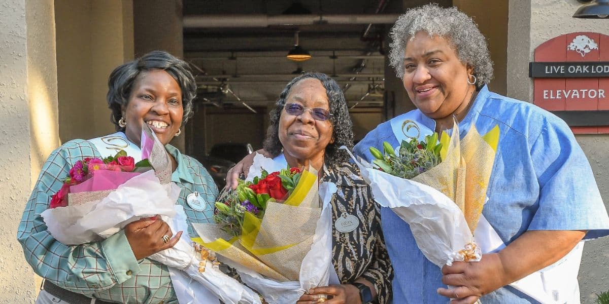 cast members holding flowers outside of building
