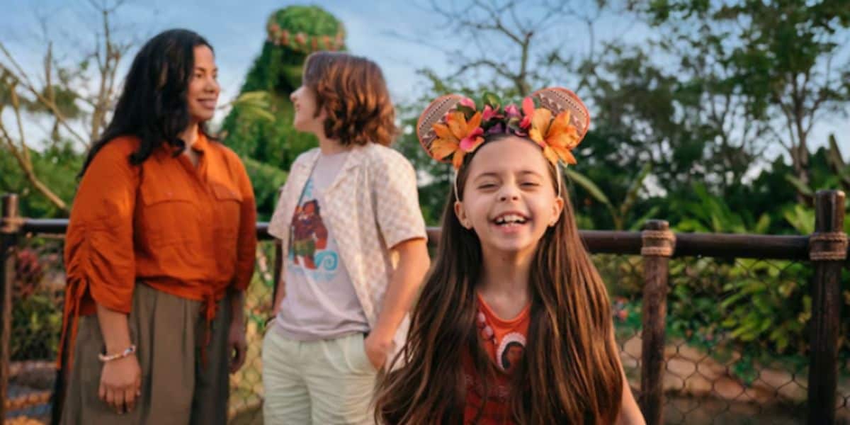 a little girl with mickey mouse ears smiles in front of EPCOT's journey of water inspired by moana attraction