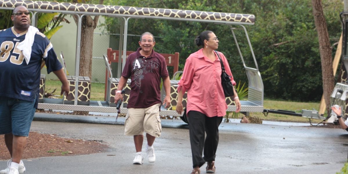 Guests walking in front of a zoo tram.