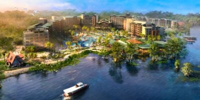 Aerial view of a lakeside resort featuring pools, vibrant gardens, and a boat ride attraction on the water. Disney Lakeshore Lodge