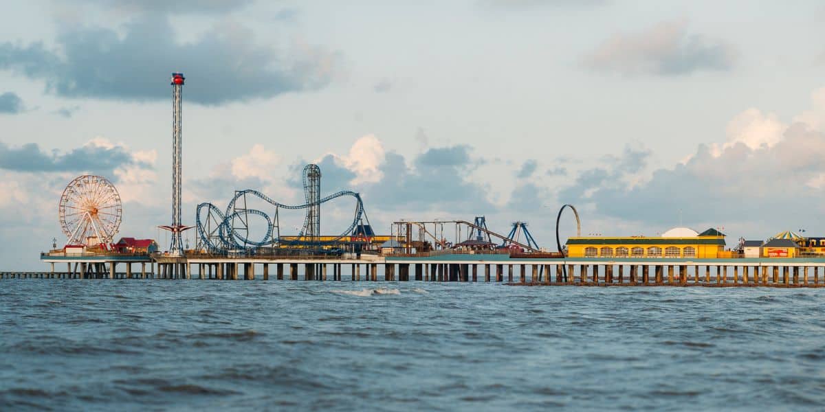 Giant roller coaster and Ferris wheel on the Santa Monica Pier, once the scene of a legendary rescue, beneath cloudy skies. Texas roller coaster rescue