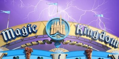 Magic Kingdom entrance sign featuring the iconic castle logo, with dramatic lightning and purple clouds setting a magical scene. Disney World weekend weather