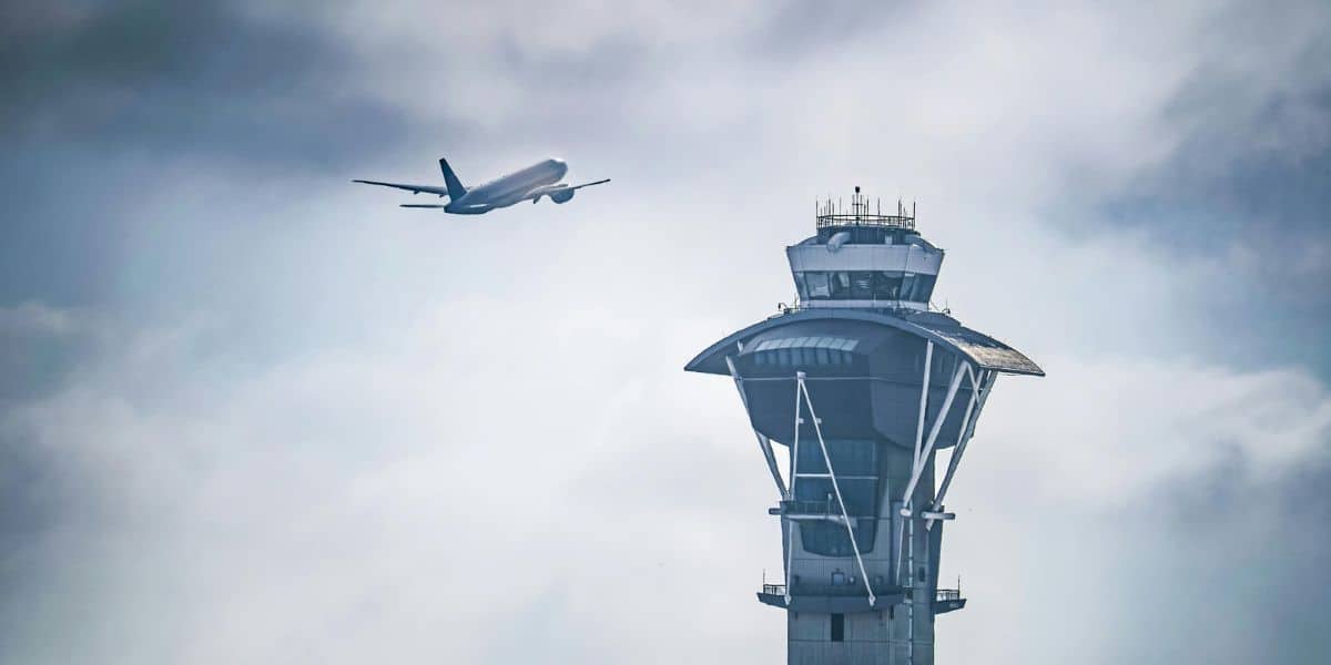 A thrilling airplane soars into the sky beside the iconic control tower, looking like a high-flying attraction at Disney’s Hollywood Studios.