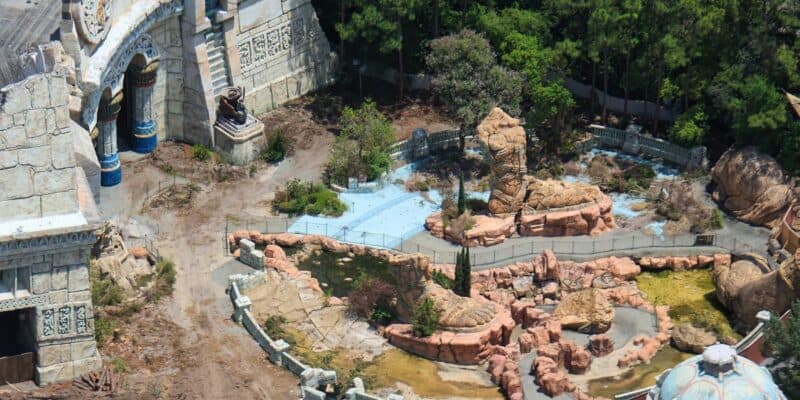 Aerial view of a deserted adventure park, featuring crumbling stone towers and rides hidden beneath lush, wild greenery. Universal Orlando Lost Continent demolition
