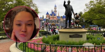 A screenshot from a video of a woman talking about being banned from Disneyland Resort, pictured in front of the Partners Statue and Sleeping Beauty Castle.