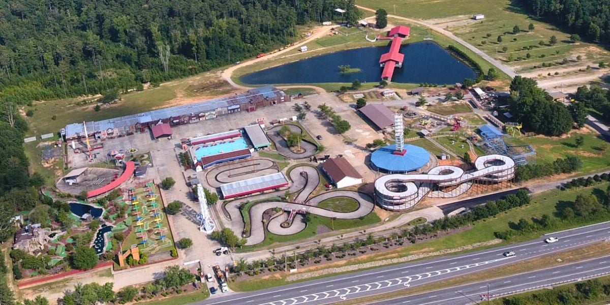 Aerial of Fun Spot Theme Park’s go-kart tracks, classic rides, and pond at sunset, moments before its grand farewell after 36 years.