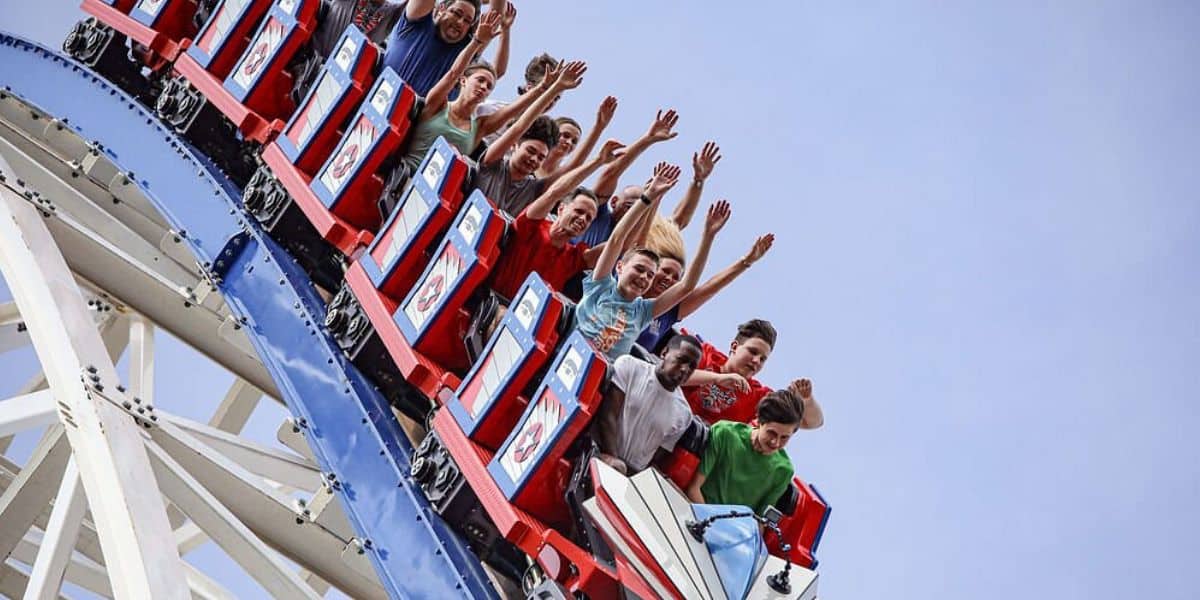 Thrill-seekers on Fun Spot’s iconic coaster, arms high and smiles wide, savor the final rides under a perfect blue sky.
