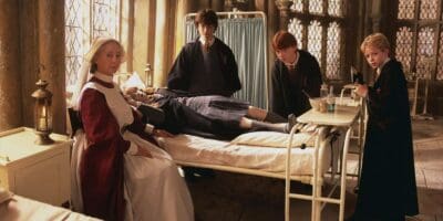 Harry Potter, Ron Weasley, Colin Creevey and Madam Pomfrey around Hermione Granger in a bed in the Hogwarts hospital wing