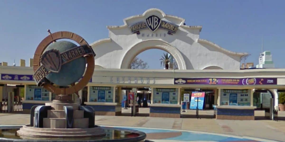 Parque Warner Madrid entrance featuring colorful ticket booths and the iconic WB logo statue welcoming guests.