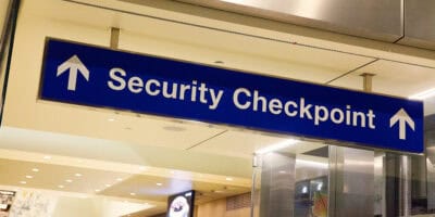 Travelers with luggage wait near a TSA security checkpoint at Orlando International Airport in Florida.