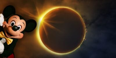 Mickey Mouse joyfully waves to guests as a spectacular solar eclipse with a bright, glowing ring and dramatic clouds unfolds overhead, bringing celestial magic and excitement to the Disney Resort experience.