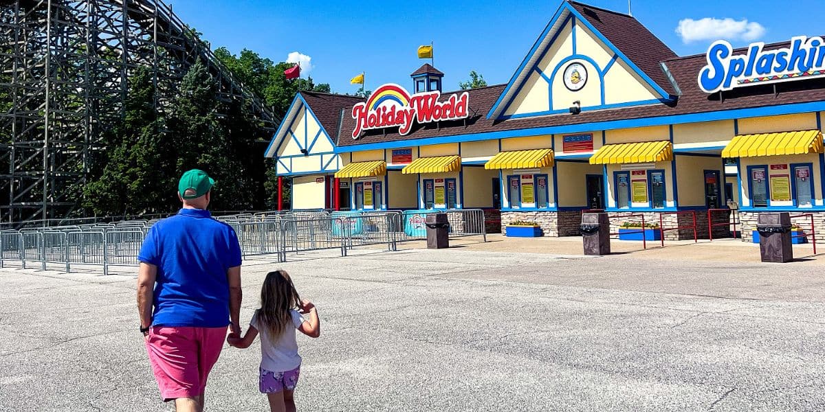 A father and daughter excitedly walk hand-in-hand toward the iconic entrance gates of Holiday World, ready to experience the park’s celebrated attractions and family-friendly entertainment.