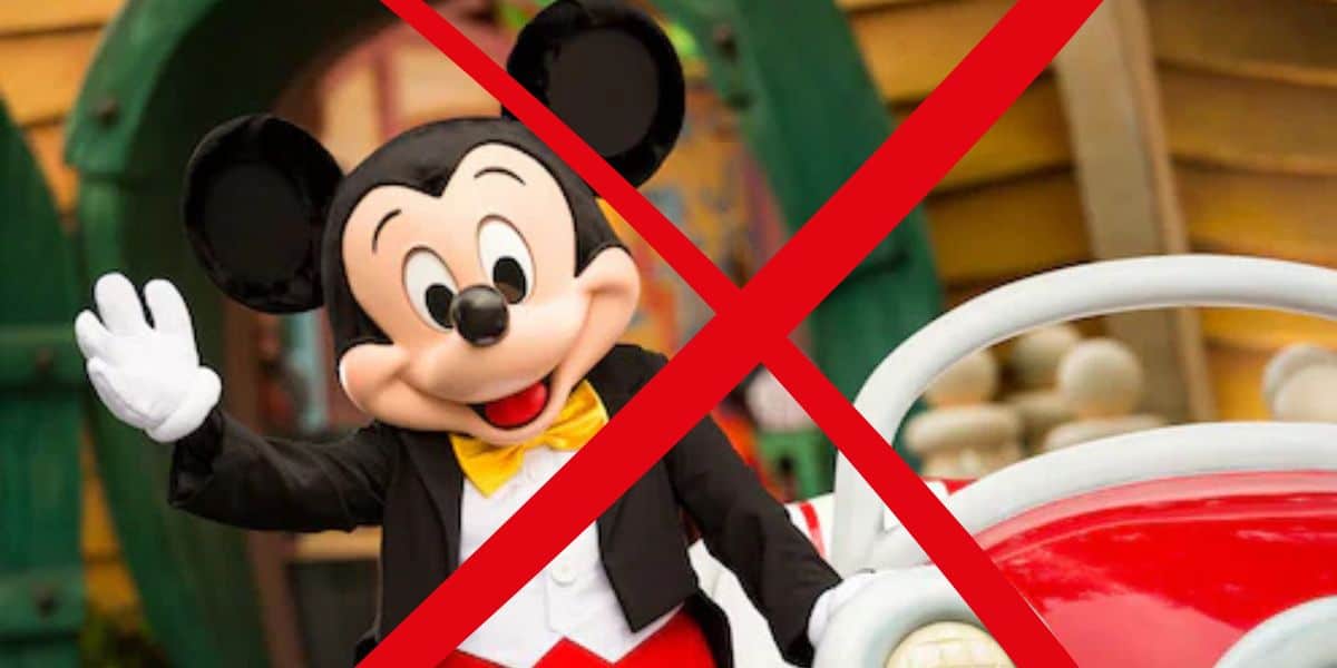 Mickey Mouse enthusiastically waving next to a bright red car, with a bold red X overlaying the scene to draw attention to challenges Disneyland cast members face concerning employee benefits.