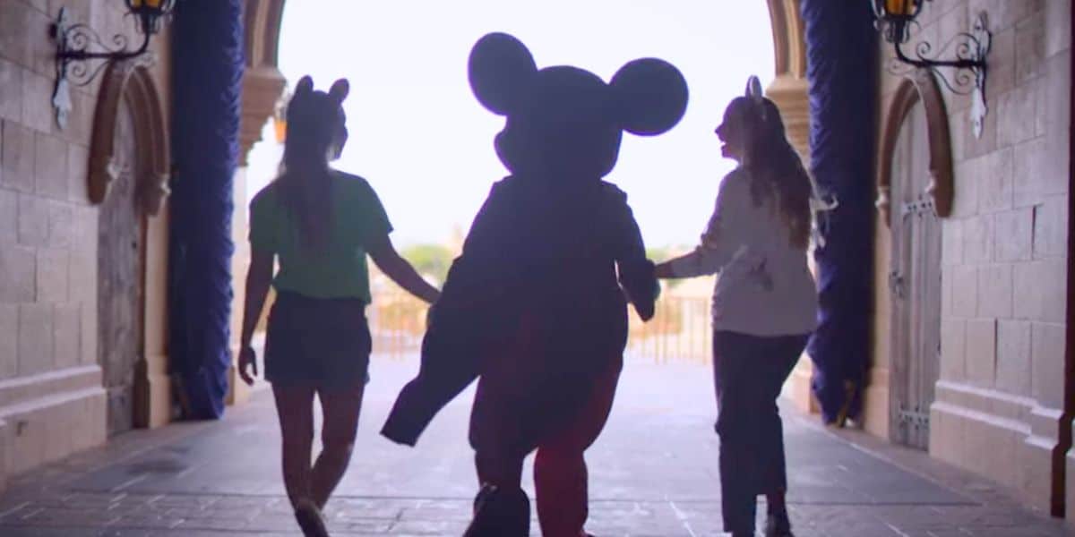 Disney World guests walk with Mickey Mouse in Magic Kingdom
