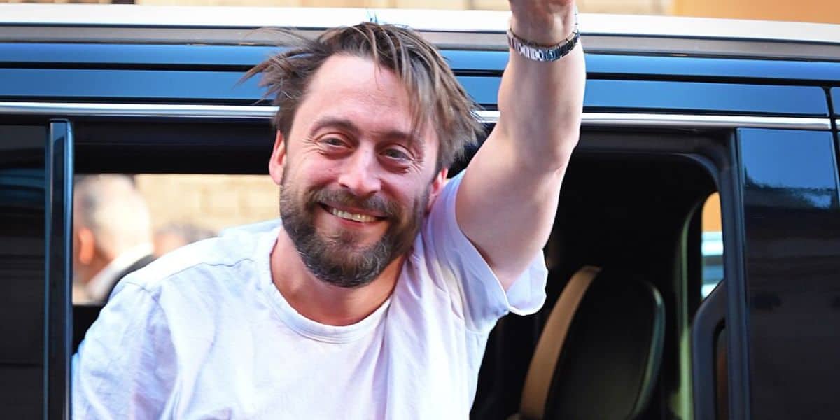Kieran Culkin waves out a car window.