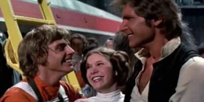 L-R: Mark Hamill as Luke Skywalker, Carrie Fisher as Princess Leia Organa, and Harrison Ford as Han Solo smiling at each other