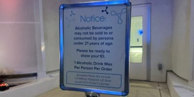 Sign at the theme park stating guests must be 21 or older to purchase alcoholic beverages, valid photo ID is required, and there’s a one drink limit per guest; sign includes a list of acceptable forms of ID.