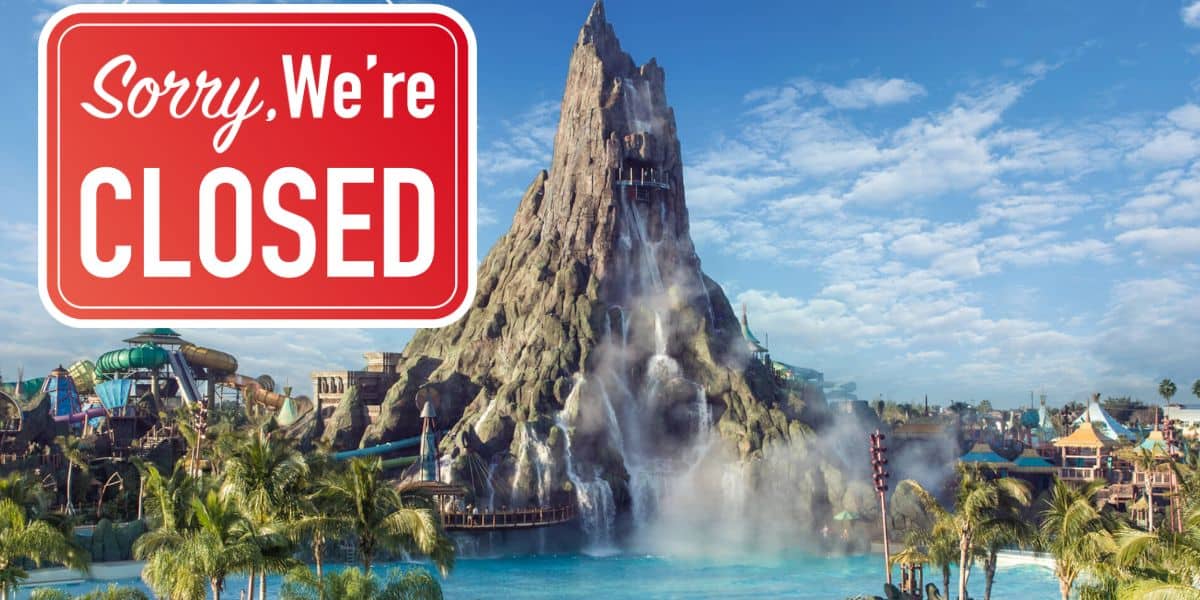 A “Sorry, We’re Closed” sign hangs over Universal’s Volcano Bay, with Krakatau’s towering volcano and twisting water slides visible in the background, capturing the emotional farewell atmosphere of the water park’s last night.