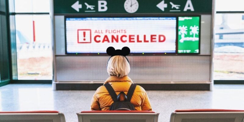 Travelers wait with luggage inside an airport terminal during flight cancellations and delays affecting Northeast airports.