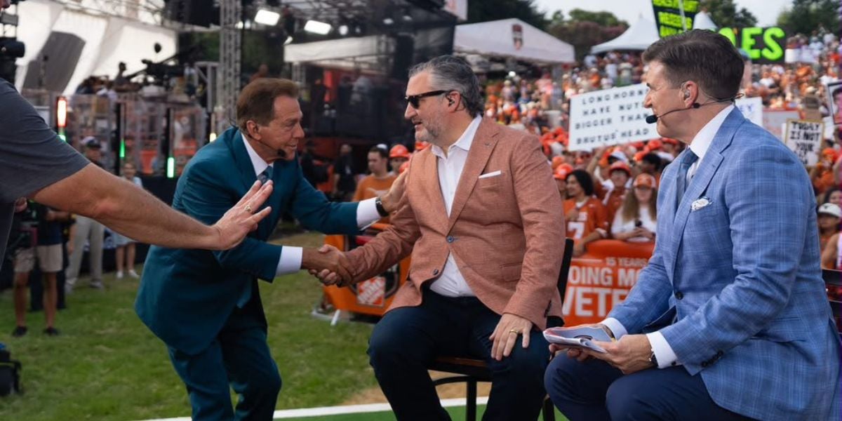 Two sports analysts in formal attire shake hands on an outdoor broadcast stage, with a charismatic host standing nearby and enthusiastic fans cheering behind them. The scene’s energy nods to the heated conversations among Disney and ESPN fans, referencing public reactions to controversial airtime decisions and ongoing debates over Disney’s evolving image.