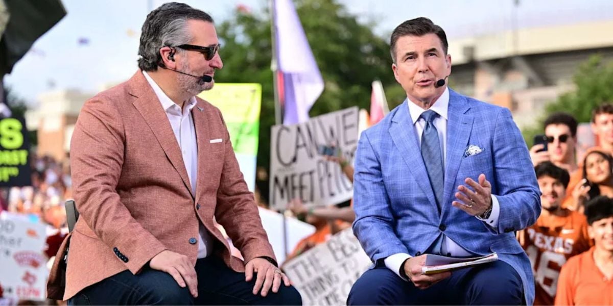 Two entertainment commentators in suits are seated on an outdoor stage, engaging in conversation as fans gather nearby holding themed signs; their discussion centers around hot topics like the recent wave of criticism towards ESPN and controversies involving Disney’s practices.