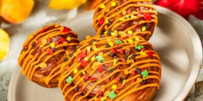 Mickey-shaped cinnamon roll covered in orange icing and sprinkles for halloween