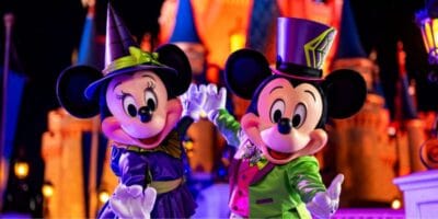 Minnie and Mickey Mouse in Halloween costumes in front of Cinderella Castle at Disney World during Halloween Party