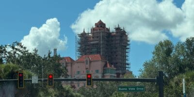 A tall pink structure under construction at a Disney park, with scaffolding visible behind a traffic light and a Buena Vista Drive street sign in the foreground.