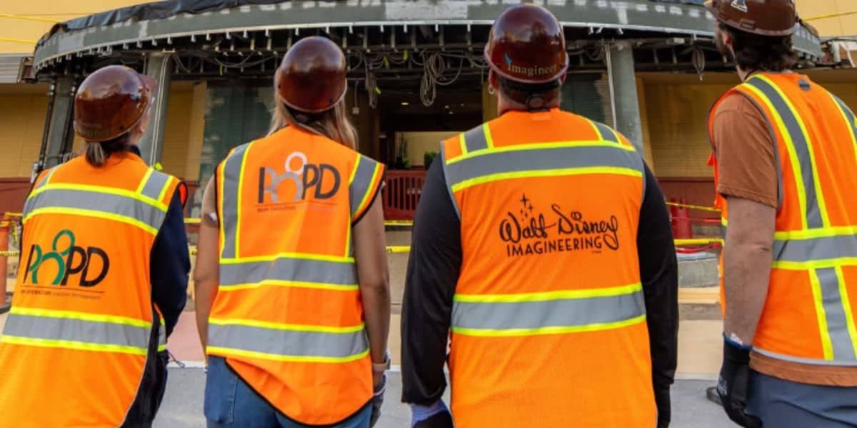 four construction workers wearing "walt disney world imagineers" work outfits