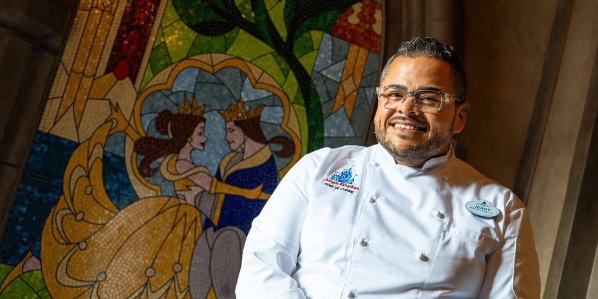 A Be Our Guest Restaurant chef posing before the Cinderella mosaic at Magic Kingdom.