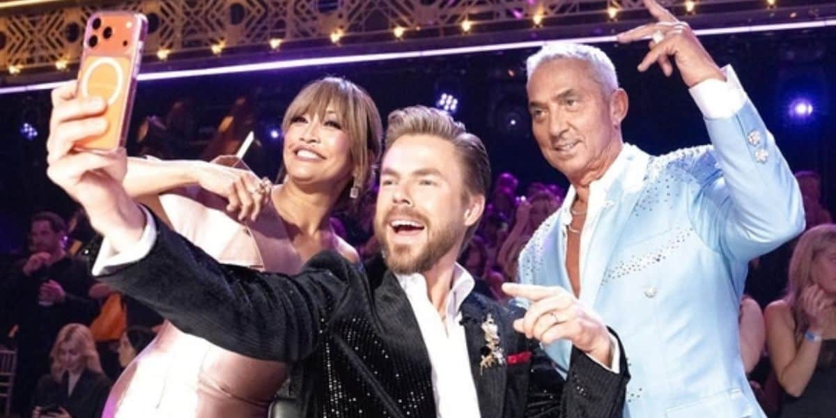 Judges Carrie Ann Inaba, Derek Hough, and Bruno Tonioli posing for a selfie on the Dancing with the Stars ballroom set.