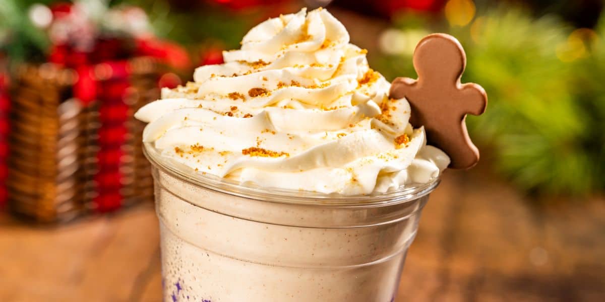Festive holiday milkshake topped with whipped cream, cookie crumbs, and a gingerbread man chocolate at a holiday celebration.