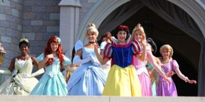 Disney princesses waving in front of Cinderella Castle at Disney World.
